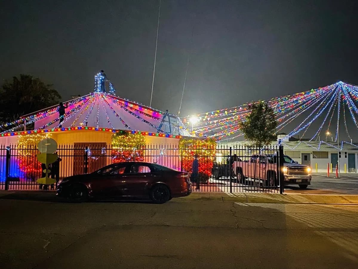 Church exterior at night covered in strings of colored festival lights fanning from the roof