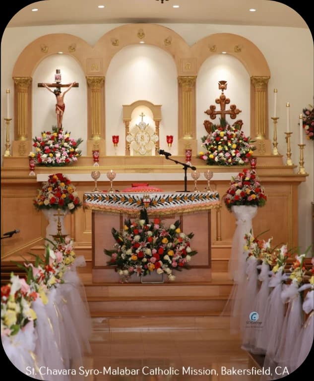 Sanctuary with crucifix, gilded tabernacle, carved cross and banks of flowers around the altar
