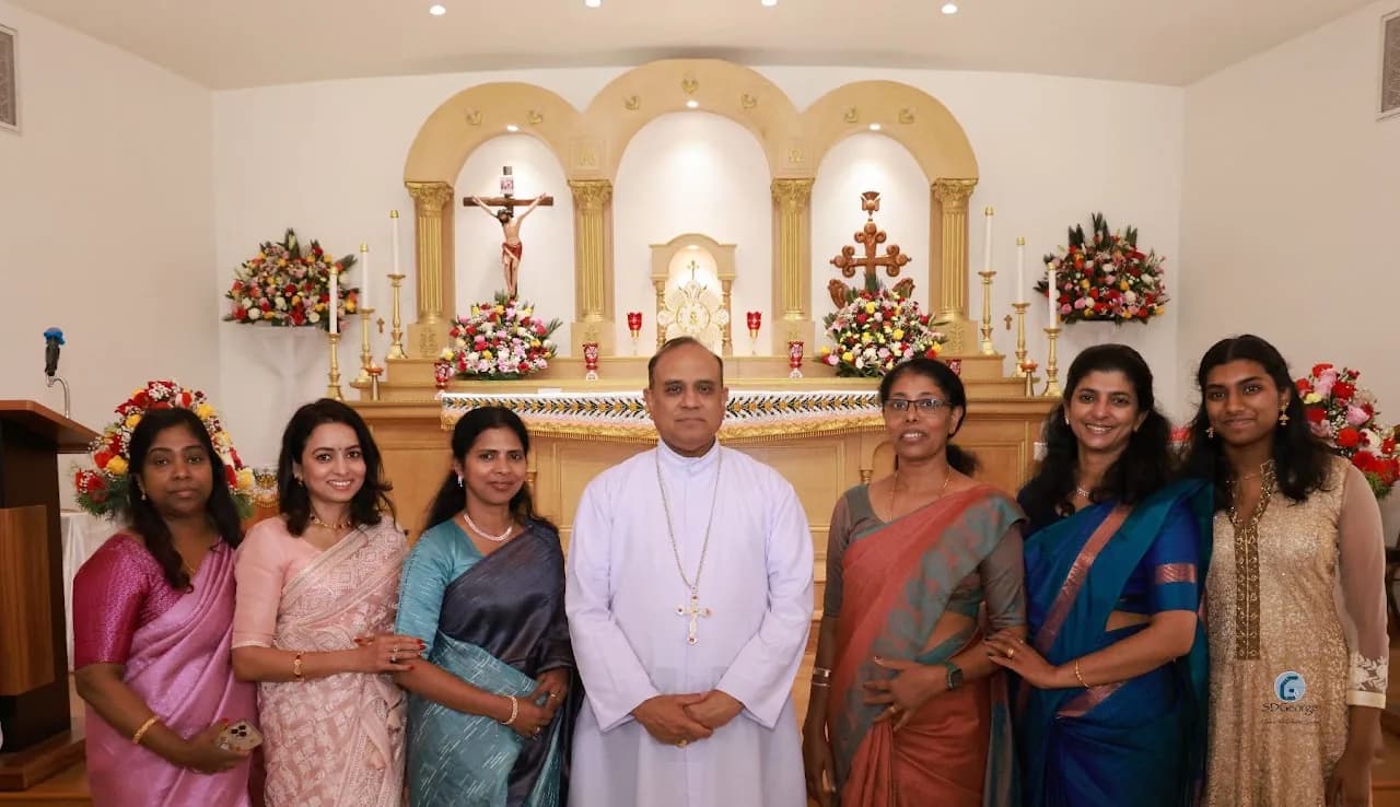Six women in saris posing with a bishop in front of the church sanctuary and altar